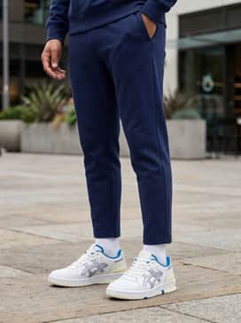 Navy blue tailored joggers with a grey oversized hoodie and a cream-colored puffer vest for a coordinated, sporty weekend look.