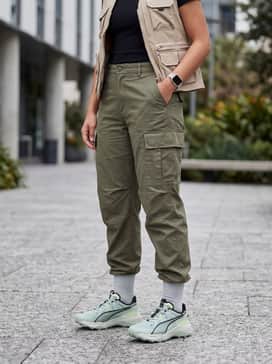 Explore Nitro 2 – A trendy gorpcore outfit with olive green utility cargo pants, a black cropped ribbed tee, and a beige technical vest.