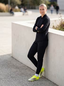 F50 Club Firm Ground  Multi Ground Soccer Cleats – Pre-game warmup gear featuring a sleek black hooded track jacket and tapered athletic joggers for comfort before the match.