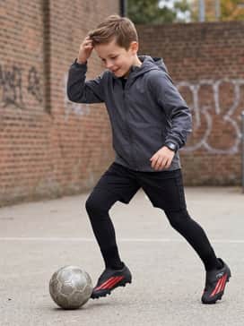 F50 Club Velcro Firm Ground  Multi Ground Soccer Boots Kids – High-performance compression leggings worn under athletic shorts with a sleek, hooded windbreaker for a modern field-ready look.