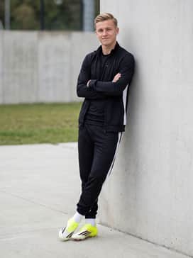 F50 Elite Artificial Ground Soccer Cleats – Pre-match warm-up: A professional-grade black tracksuit with white side stripes and a fitted athletic base layer for maximum movement.
