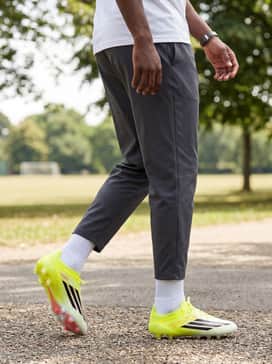 F50 Elite Artificial Ground Soccer Cleats – Practice drills: A vibrant yellow technical tee that echoes the shoe's primary color, paired with charcoal grey athletic shorts and a lightweight windbreaker.