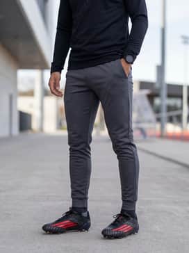F50 Elite Firm Ground Football Boots – Professional training gear consisting of a sleek black quarter-zip technical top, slim-fit charcoal training joggers, and a matching red headband for a cohesive look.