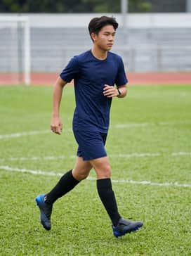 A full match-day kit consisting of a navy blue moisture-wicking jersey, matching athletic shorts, and high-performance black grip socks to highlight the electric blue soleplate.