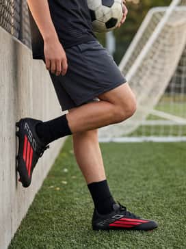 F50 League Firm Ground  Multi Ground Soccer Boots Kids – Warm-up attire with a bold graphic athletic t-shirt, breathable mesh shorts in a charcoal hue, and a matching team baseball cap.