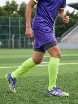 F50 League Firmmultiground Cleats Kids – A full team soccer uniform featuring a moisture-wicking jersey, lightweight shorts, and high-performance compression socks that match the purple or lime green accents.