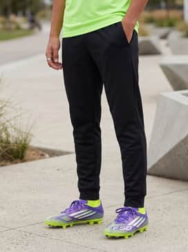 A neon green training tee paired with black tapered joggers for early morning drills, ensuring the pants do not interfere with the cleat's studs.