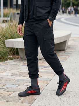 Dark grey techwear cargo pants, a black oversized hoodie with minimal red text, and a utility vest for a modern urban street style.