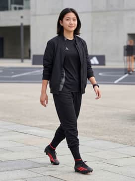 F50 League Mid Cut Firm Ground  Multi Ground Football Boots – A sleek professional match kit with a black technical jersey, red-piped shorts, and over-the-calf black performance socks.
