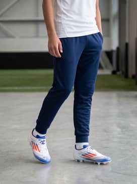 F50 League Multiground Soccer Cleats – A lightweight white training tee paired with navy blue athletic joggers for cooler morning practice sessions.