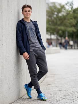 A post-game casual ensemble with charcoal gray tech-fleece joggers, a graphic Messi-branded t-shirt, and a sleek navy windbreaker.