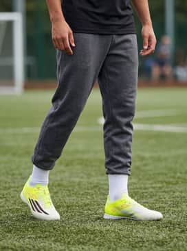 F50 Pro Turf Soccer Shoes – A sleek cold-weather training ensemble consisting of a charcoal grey tech-fleece quarter-zip pullover and matching tapered joggers to allow the yellow shoes to stand out.