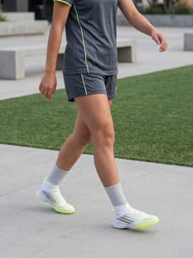 F50 Sparkfusion League Mid Cut Turf Soccer Shoes Kids – A full matching team soccer kit consisting of a moisture-wicking jersey and athletic shorts in white or charcoal grey to let the lime green accents pop.