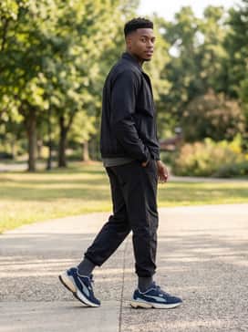 Black nylon joggers and a matching technical windbreaker over a graphic tee for a contemporary athletic-inspired ensemble.