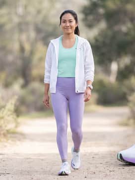 High-performance lavender compression leggings paired with a racerback mint green technical tank top and a lightweight white windbreaker for an early morning trail run.