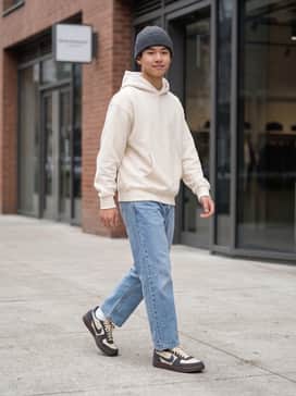 Relaxed straight-leg light wash denim paired with an oversized cream hoodie and a charcoal grey beanie to mirror the shoe's contrast.