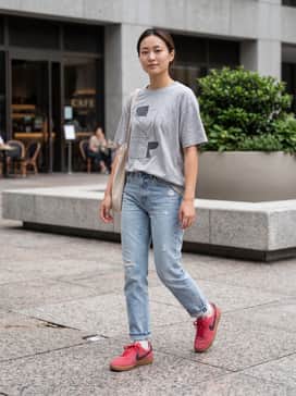 Light-wash distressed straight-leg jeans paired with an oversized vintage graphic tee and a neutral-toned canvas tote for a classic 90s-inspired look.