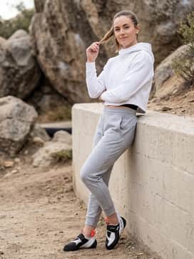 Athletic gym attire consisting of charcoal grey tapered joggers, a white cropped hoodie, and a high-performance supportive sports bra.