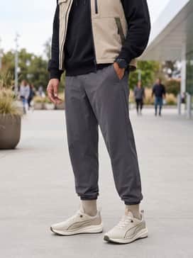 Flare Pro Trail Puretrex – A technical streetwear outfit with charcoal tapered tech joggers, a black oversized hoodie, and a beige utility vest.