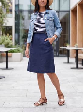 Flash – Style with a navy blue knee-length A-line skirt and a tucked-in striped breton top. Add a light denim jacket and a straw sun hat for a classic nautical-inspired summer outfit.