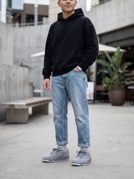 Flight Court – Relaxed-fit light blue denim jeans with a neat cuff at the ankle, styled with an oversized black graphic hoodie and a silver watch to emphasize the clean grey silhouette.