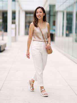 Flowt Wedge Lx – High-waisted white linen trousers paired with a tucked-in silk camisole in a soft metallic hue and a tan crossbody bag.