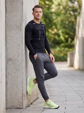 Style with charcoal grey performance leggings, a black compression long-sleeve shirt, and a reflective running vest for high-visibility early morning or evening sessions.
