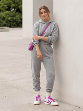 Relaxed-fit grey joggers and a matching cropped hoodie, accented with a magenta crossbody bag to pull the vibrant shoe color through the entire look.