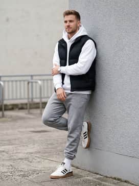 Forum Low Shoes – Grey fleece joggers paired with a crisp white oversized hoodie and a black puffer vest for a clean, off-duty athletic look.