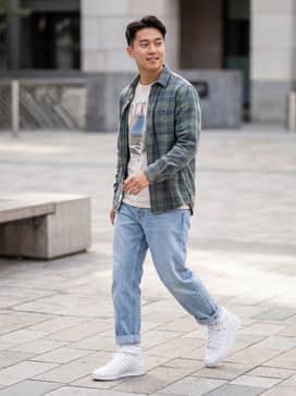 Light wash relaxed-fit jeans rolled at the cuff to show the strap, paired with a vintage graphic tee and an unbuttoned flannel shirt for a classic 90s aesthetic.