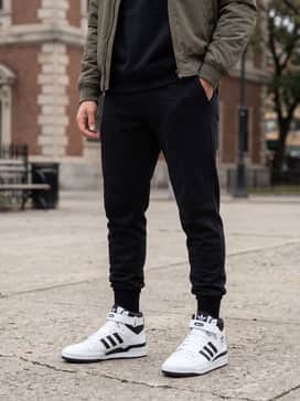 Forum Mid Shoes – Black tapered joggers, a matching black oversized hoodie, and a technical olive bomber jacket for a modern, monochrome athleisure ensemble.