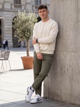 Olive green cargo pants with cuffed hems to highlight the mid-top silhouette, paired with a cream-colored heavyweight crewneck sweatshirt.