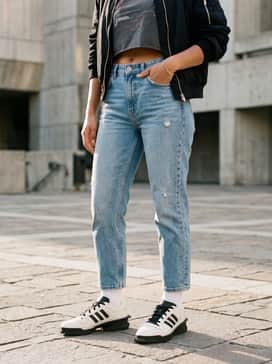 High-waisted light-wash boyfriend jeans with a cropped vintage graphic tee and a black nylon bomber jacket to emphasize the 90s aesthetic.