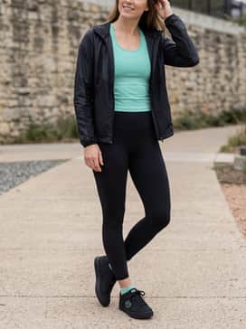 High-waisted black athletic leggings matched with a teal racerback tank top and a sleek windbreaker for a cohesive, performance-driven outfit.