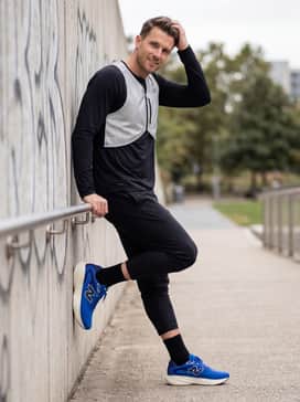 Reflective silver running vest layered over a black long-sleeve thermal base layer with black athletic joggers.