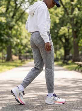A relaxed weekend style using tapered grey joggers, a cropped white hoodie, and a matching navy baseball cap for a coordinated aesthetic.
