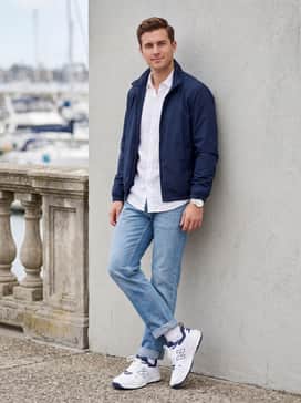 Fresh Foam X 1007 – Light-wash denim jeans with a rolled cuff and a navy blue windbreaker jacket over a white linen shirt for a nautical-inspired casual outfit.