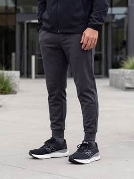 An elevated athleisure look pairing charcoal tapered joggers with a crisp white oversized heavy-weight cotton t-shirt and a lightweight black windbreaker.