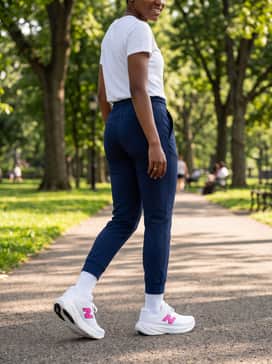 Tapered navy blue performance joggers with a tucked-in white graphic tee and a neon pink headband to pull the accent color through the look.