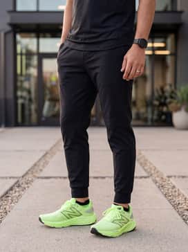 Tapered black tech-fleece joggers styled with a fitted black long-sleeved performance top and a sleek matte black sports watch.