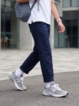 A classic school ensemble featuring navy blue chino trousers, a crisp white polo shirt, and high-cut white socks to accentuate the sneaker's chunky silhouette.