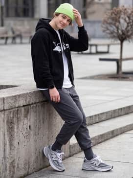 Fuelcell 990v6 Lace – A trendy streetwear look with relaxed light-wash denim jeans, an oversized black graphic hoodie, and a neon-colored beanie to add a pop of contrast to the grey tones.