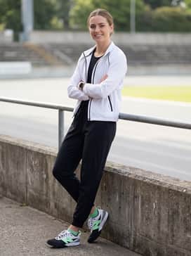 Fuelcell Flited – A pre-race warm-up ensemble including tapered black athletic joggers and a lightweight white zip-up windbreaker.