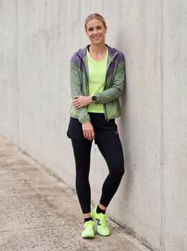 Training session ensemble with black compression tights, a neon yellow mesh tank top, and a lightweight windbreaker.
