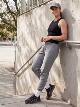 A comfortable weekend athleisure set with grey tapered sweatpants, a black ribbed tank top, and a matching baseball cap for a relaxed, sporty vibe.