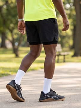 An active summer ensemble including 7-inch inseam black athletic shorts, a vibrant neon-yellow dry-fit tee, and white crew-length socks to lean into the athletic look.