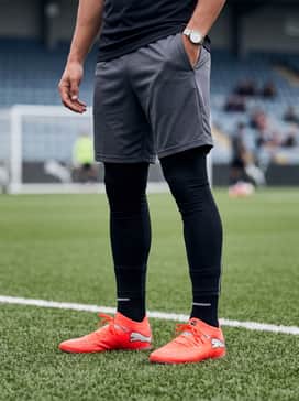 A streamlined training outfit consisting of a charcoal grey quarter-zip tech top and tapered black athletic track pants for a modern, sleek look during drills.