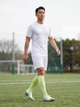 A full professional match kit featuring a sleek white jersey, matching athletic shorts, and high-performance lime green compression socks to highlight the cleat's accents.