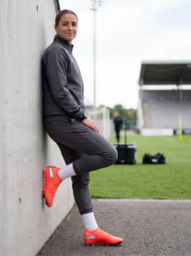 A lightweight windbreaker and matching tracksuit pants in a dark neutral shade to let the bright cleats be the focal point.