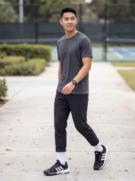 A professional court look featuring white moisture-wicking tennis shorts, a black technical polo, and white crew socks pulled mid-calf.